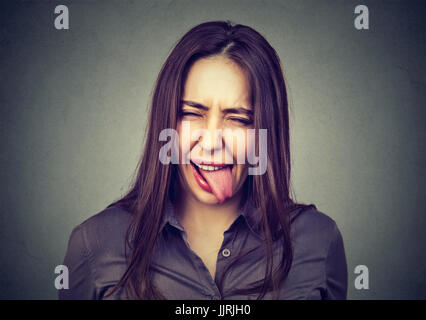 Portrait der schönen Frau in Freizeitkleidung zeigt ihre Zunge Stockfoto