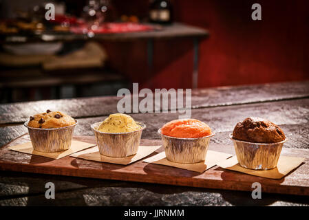 frisch gebackene Muffins am Tisch in gemütlicher Coffeeshop innen gemischt Stockfoto