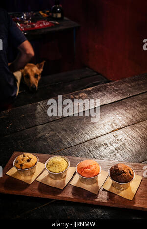 frisch gebackene Muffins am Tisch in gemütlicher Coffeeshop innen gemischt Stockfoto