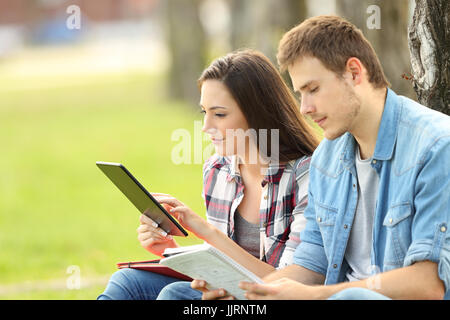 Zwei Studenten studieren auf Linie und Notenlesen sitzen auf dem Rasen in einem park Stockfoto