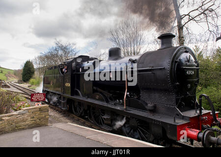 Motor Treiber in der Dampflok schnaufend Rauch (BR Midland Railway 4F 0-6-0 43924) zieht in die Station - Keighley & Worth Valley Railway, England, UK. Stockfoto