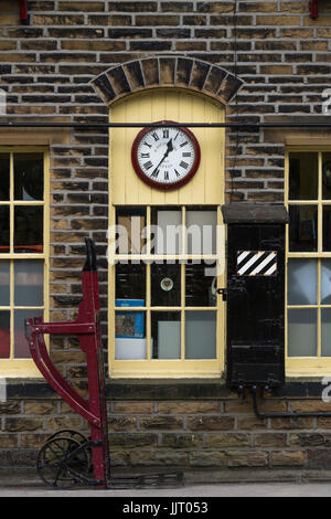 Detail des alten Booking office, Uhr & Gepäck Trolley auf der Plattform - historische Oxenhope Station, in Keighley und Worth Valley Railway Station, England, UK. Stockfoto