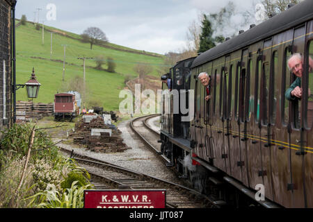 Zug-Fahrer-Guides Dampf Lok 4F 0-6-0 43924 in Station, 2 Passagiere mit Köpfen aus Reisebus - Keighley & Wert Valley Railway, England, UK. Stockfoto