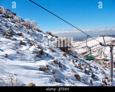 Felsiger und verschneiter Hang steht neben einem Skilift Stuhl auf Einfassung Hermon in Israel. Stockfoto