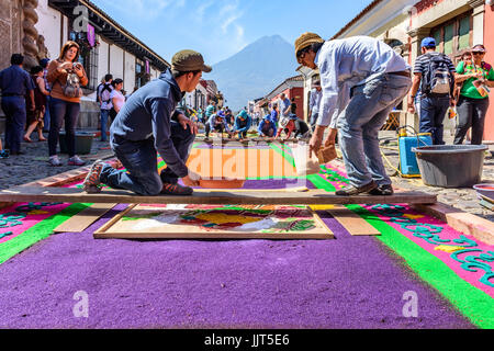 Antigua, Guatemala - März 25, 2016: Leute beobachten, während Einheimische gefärbte Sägespäne Karfreitag Teppiche in Street für Prozession in der kolonialen Stadt machen Stockfoto