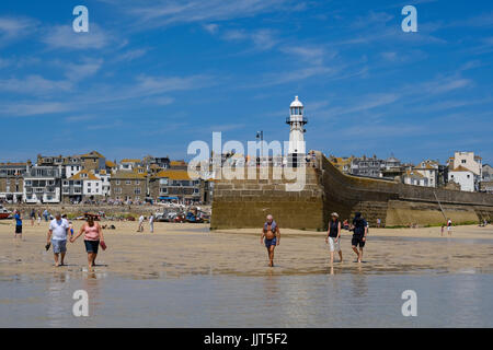 Urlauber genießen Sie einen Spaziergang entlang des Ufers im Hafen von St. Ives, Cornwall Stockfoto