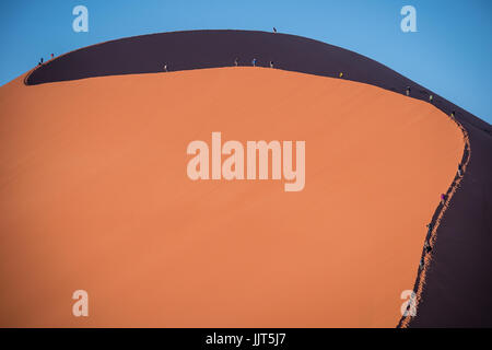 Menschen klettern riesige Dünen im Namib-Naukluft National Park in Namibia, Afrika. Enthält einige der größten Sanddünen der Welt, Sossusvlei. Stockfoto
