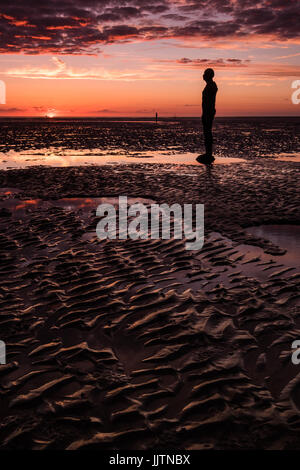 Antony Gormley Gusseisen Statuen, Bestandteil der Installation benannt "Woanders", am Strand von Crosby in Sefton bei Sonnenuntergang. Stockfoto