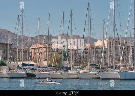 Palermo, Sizilien, Italien, Juli 15 / 2017 Palermo Cala Hafen, zwei Männer in einem Boot, Rudern und Boote vertäut im Hafen, Stadt im Hintergrund - Mittelmeerraum Stockfoto