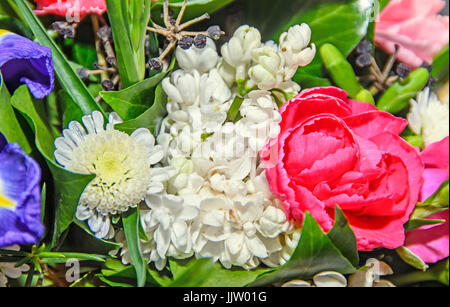 Blumenarrangement mit farbigen Blumen Rosen, Iris, Chrysanthemen, Nelken, grüne Blätter. Stockfoto