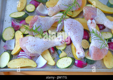 Backform mit rohem Hühnerfleisch Beine, Zucchini, rote Zwiebeln und Fingerling Kartoffeln, gewürzt und fertig backen Stockfoto