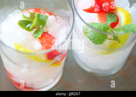 Aufwand für zwei Gläser Früchten aromatisiertes Wasser mit zerstoßenem Eis, Erdbeeren, Zitrone und Minze Stockfoto