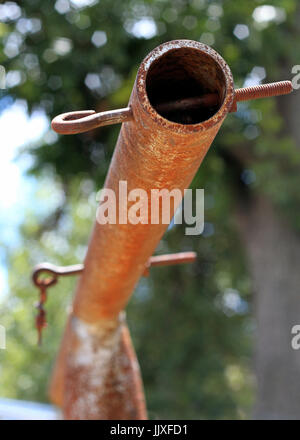 Ein alt und verrostet Wäscheleine Querstange mit Auge Schrauben und Bäume im Hintergrund. Stockfoto