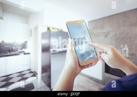 Unbekannte Frau Hand mit Fernbedienung home System auf Handy. Stockfoto