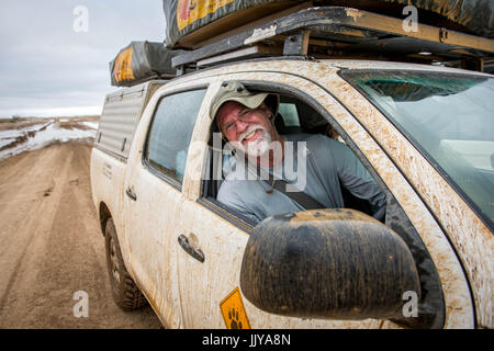 Mann posiert für ein Foto auf dem Beifahrersitz eines off-Road-Fahrzeug auf Namibias Skelettküste, Afrika. Stockfoto