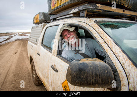 Mann posiert für ein Foto auf dem Beifahrersitz eines off-Road-Fahrzeug auf Namibias Skelettküste, Afrika. Stockfoto