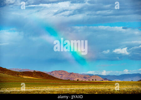 Ein Regenbogen wölbt sich über Berglandschaft in der Namib-Wüste, befindet sich in Namibia, Afrika. Stockfoto