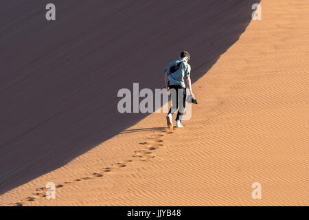 Ein Tourist beginnt aufsteigend Düne 45, einem alten Düne in den Soussuvlei Salzpfanne im Namib-Naukluft-Nationalpark befindet sich in Namibia, Afrika. Stockfoto