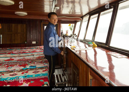 Vietnamesische männlichen Lenkung cruise Boot mit seinem Bett im Hintergrund - Ha Long Bay - 9. März 2017 Stockfoto