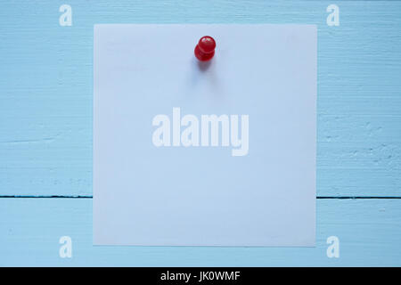 small square piece of blank paper pinned to the wooden board wall. blue background Stockfoto
