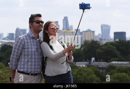 Primrose Hill Besucher nehmen eine "Selfie" vor dem Hintergrund der Londoner City in der Ferne hinter ihnen. Stockfoto