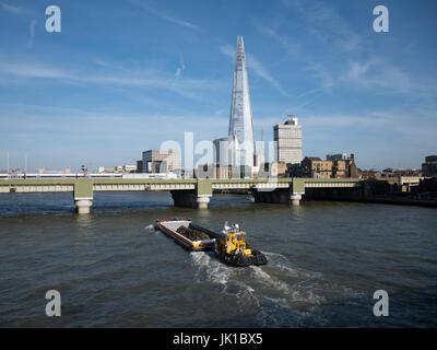 Schlepper auf Themse Bauschutt unter Cannon Street Eisenbahnbrücke mit der Scherbe in den Hintergrund verschieben Stockfoto