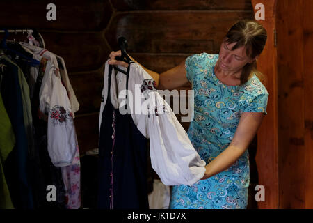 Tatjana Tufeneva Nachfahrin der Gemeinschaft der Altgläubigen, die in ihrem Haus im Dorf Solonovka im Smolenski-Bezirk in der Altai-Region in Westsibirien, Russland, traditionelle Sarafan-Kleidung inspiziert Stockfoto