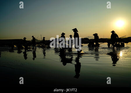 Silhouette der Arbeitnehmer sammeln Rohsalz in der Morgensonne mit einer Schubkarre aus Salz Bauernhof als Zutat für Lebensmittel in Asien verwendet werden. Stockfoto