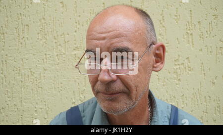 Porträt eines lächelnden Schuhmachers in Form, zur gelben Wand stehend arbeiten. Stockfoto