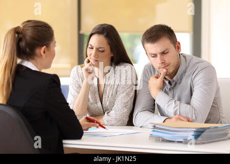 Büroangestellter teilnehmen und mit Vertrag versucht, einen verdächtigen Paar sitzen in einem Schreibtisch im Büro zu überzeugen Stockfoto