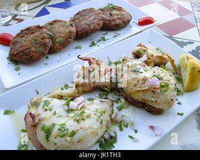 Gegrillten frischen Tintenfisch mit Olivenöl und Zitrone und Zucchini Krapfen im Hintergrund, Chania auf Kreta Insel Griechenlands Stockfoto