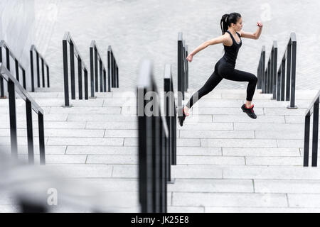 Seitenansicht der sportliche junge Frau in Sportkleidung auf Stadion Treppen laufen Stockfoto