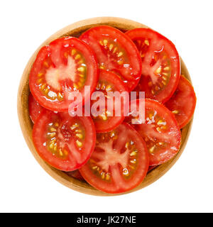 Tomatenscheiben in Holzschale. Essbare reif und rohe Frucht von Solanum Lycopersicum mit rot, in dünnen Splittern schneiden. Isolierte Makrofoto Essen. Stockfoto