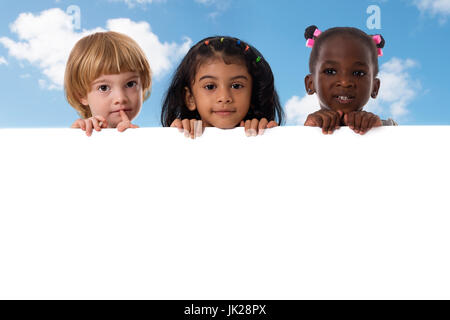 Gruppe der multirassischen Kinder Portrait im Studio mit White Board auf blauen Himmel Hintergrund Stockfoto