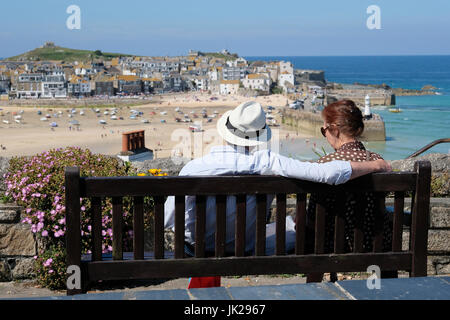 Paar saß auf Bank genießen den Blick über St. Ives, Cornwall Stockfoto