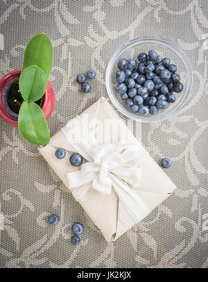 Zusammensetzung der ein Geschenk in Eco Paket, Heidelbeeren in eine Schüssel geben und eine kleine Pflanze in einen Blumentopf Stockfoto