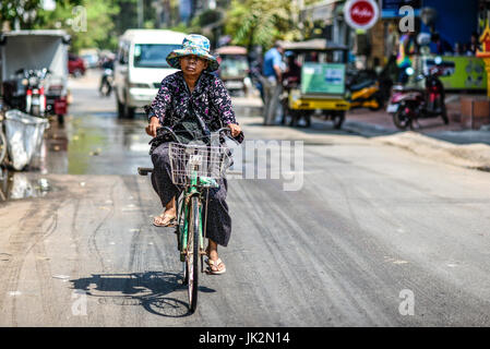 Siem Reap, Kambodscha, 19. März 2016: eine Frau mit dem Fahrrad auf einer Straße in Kambodscha Stockfoto