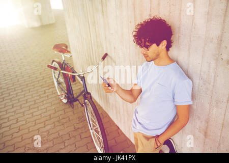 Mann mit Smartphone und fixed-Gear-Bike auf Straße Stockfoto