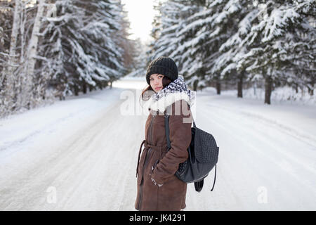 Asiatische Frau mit Rucksack auf verschneiten Straße Stockfoto