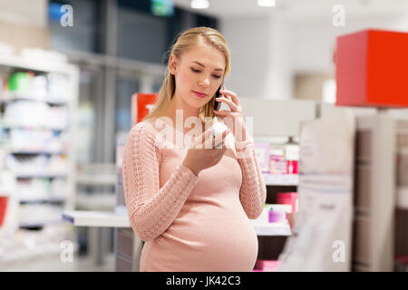 glücklich schwanger Frau mit Smartphone in Apotheke Stockfoto