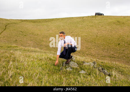 Lächelnd kaukasischen Geschäftsmann Gras hocken Stockfoto