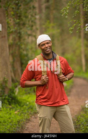 Afrikanische amerikanische Mann auf Pfad im Wald mit Rucksack Stockfoto