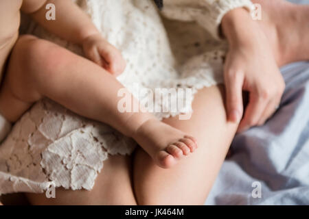 Bein der kaukasischen jungen sitzen auf dem Schoß der Mutter Stockfoto