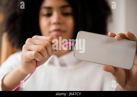 Afrikanische amerikanische Frau, die Verbindungskabel zum Handy Stockfoto