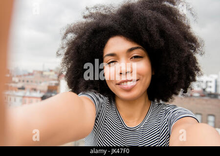 Lächelnde afroamerikanische Frau posiert für Selfie auf Dach Stockfoto