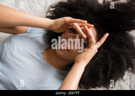 Afroamerikanische Frau im Bett Abschirmung Augen Stockfoto