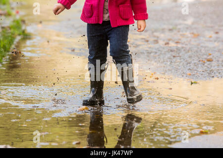 Kaukasische Mädchen tragen Stiefel in Pfütze planschen Stockfoto