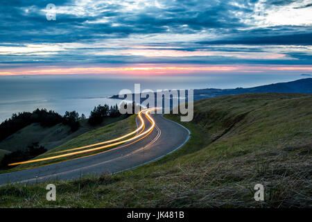 Lichtspuren auf kurvenreichen Straße in der Nähe von Meer Stockfoto