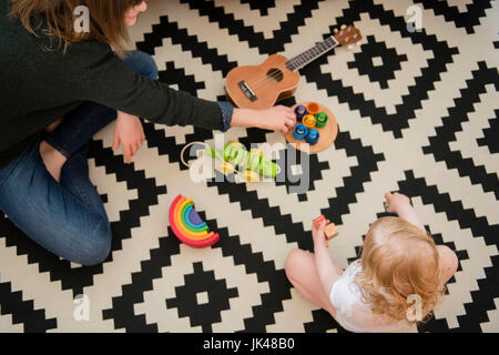 Kaukasische Mutter und Tochter sitzen am Boden spielen mit Spielzeug Stockfoto