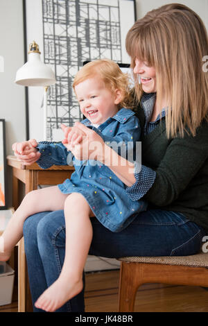 Kaukasische Mutter mit Tochter im Schoß sitzen zu spielen Stockfoto